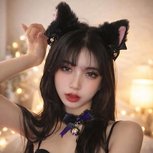 Peut inclure: Serre-tête noir avec des oreilles de chat à l'intérieur rose, des nœuds noirs et des clochettes dorées. Un ras du cou noir assorti avec un ruban violet et un pendentif clochette doré. Accessoires portés avec un haut noir.