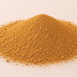 Peut inclure: Un monticule conique de poudre fine brun doré à la texture granuleuse. La substance semble sèche et uniforme en couleur, formant un tas symétrique qui se rétrécit vers un sommet arrondi, présentant un pigment chaud, terreux et constant.