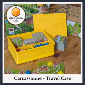 Op de afbeelding: Een felgele plastic opbergorganizer voor het bordspel Carcassonne, voorzien van een deksel met een rasterpatroon en de cijfers 19 tot en met 49 in reliëf. De doos bevat verdeelde vakken met stapels vierkante speeltegels en kleine houten figuren.