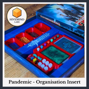 May include: A blue plastic board game organiser insert for the game Pandemic, featuring moulded compartments for game components including coloured cubes, tokens, and card slots. The insert is designed to fit inside the game box, which is visible.