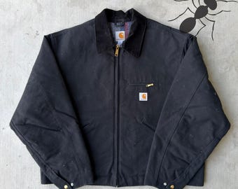 May include: Black Carhartt jacket with a corduroy collar and a full-length zipper. The jacket features a small square logo patch on the chest pocket and a gold zipper. The jacket has two front pockets and buttoned cuffs.