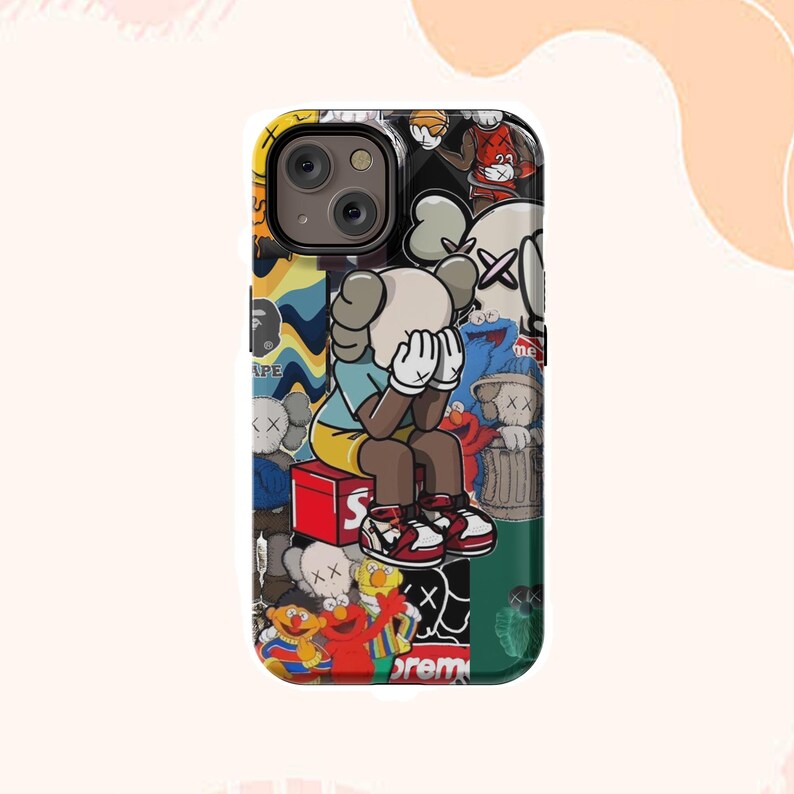 May include: A vibrant phone case with a collage of cartoon characters and graphic designs. The case has a black camera cutout and a design that includes a figure with hands covering its face, and the word "APE".