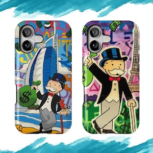 May include: Two phone cases with colorful Monopoly-themed designs. One case features a cityscape with a Monopoly man holding a money bag. The other case shows the Monopoly man with the Eiffel Tower in the background, also holding a money bag.