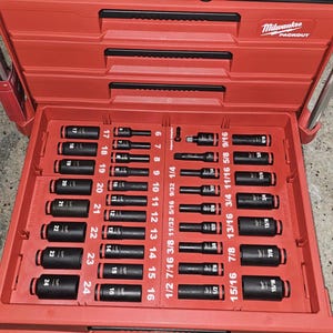 May include: A red Milwaukee Packout tool chest with an open drawer containing a black socket set organized in a custom tray. The tray features labeled slots for metric sizes 6 through 24 and imperial sizes 1/4 through 15/16, with black sockets.