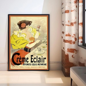 May include: A framed vintage poster advertising Crème Eclair. The image shows a woman in a yellow dress, holding a product container. The poster has a black frame with an orange border and includes French text. The colour scheme includes yellow, red, and black.