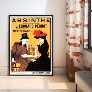 Puede incluir: Un póster vintage de Absenta enmarcado en un marco negro. El póster presenta a un hombre y una mujer en una mesa, con botellas y texto en amarillo y negro. La mujer lleva un sombrero rojo y un vestido negro.