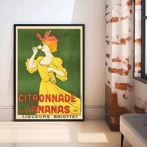 Könnte beinhalten: Gerahmtes Vintage-Werbeplakat für "Citronnade à l'Ananas", das eine Frau in gelbem Kleid und Hut zeigt, die aus einem Glas trinkt. Das Plakat hat einen grünen Hintergrund und den Text "Liqueurs Briottet".