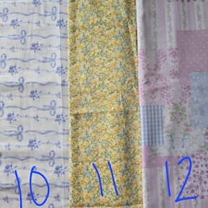 May include: Three fabric swatches with different patterns. The first is white with blue ribbons and floral accents. The second is yellow with a small floral pattern. The third is a patchwork design with pink, blue, and white floral and gingham patterns.