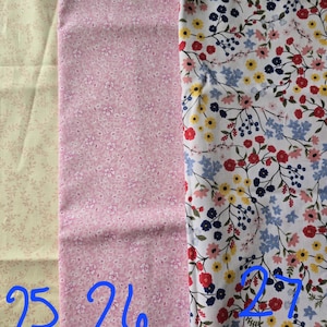 May include: Three fabric swatches with floral patterns. The first is a light beige with small pink sprigs. The second is pink with small white flowers. The third is white with red, yellow, blue, and navy flowers.