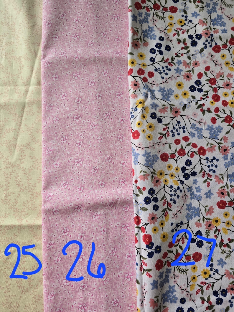 May include: Three fabric swatches with floral patterns. The first is a light beige with small pink sprigs. The second is pink with small white flowers. The third is white with red, yellow, blue, and navy flowers.