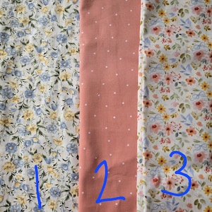 May include: Three fabric swatches: one with blue and yellow floral print, a second with a peach background and white polka dots, and a third with a floral pattern in yellow, pink, and blue.