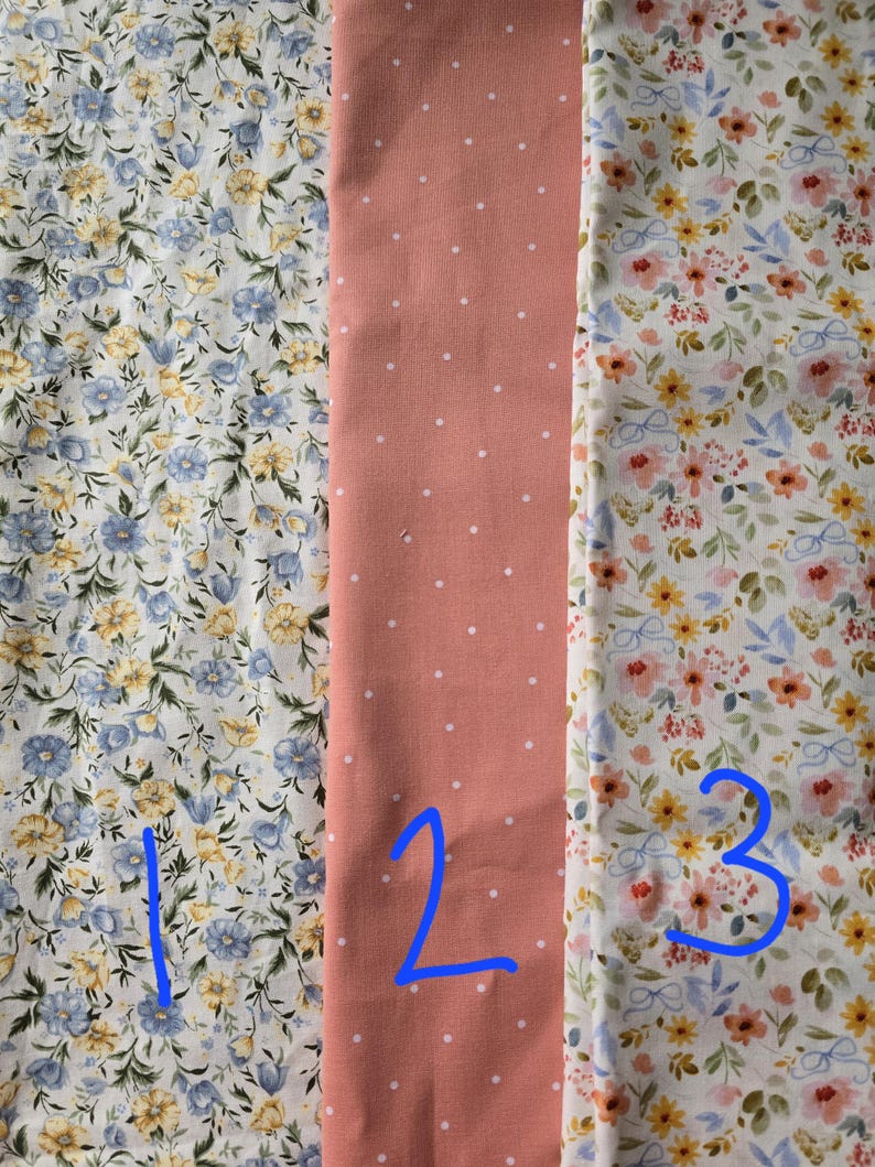 May include: Three fabric swatches: one with blue and yellow floral print, a second with a peach background and white polka dots, and a third with a floral pattern in yellow, pink, and blue.