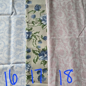 May include: Three fabric swatches with different floral patterns. One is light blue with a floral design, the second is beige with blue roses and green leaves, and the third is pink with a floral pattern. Numbers 16, 17, and 18 are written in blue.
