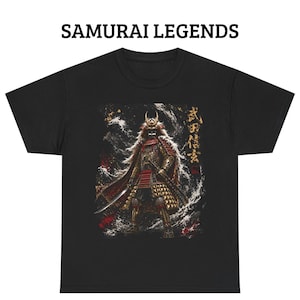 Puede incluir: Camiseta negra con una ilustración detallada de un guerrero samurái con armadura completa, con una espada y una capa fluida. El diseño incluye detalles dorados y rojos, y el texto "SAMURAI LEGENDS" está impreso en la parte superior.