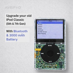 Könnte beinhalten: Ein iPod Classic mit transparentem Gehäuse, das ein Menü auf dem Bildschirm anzeigt. Das Gerät hat ein schwarzes Click-Wheel und eine sichtbare Leiterplatte. Text: "Upgrade your old iPod Classic (5th & 7th Gen) With Bluetooth & 3000 mAh Battery."
