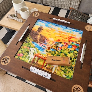 May include: A wooden dominoes game set with a colorful landscape design. The set includes a wooden frame, dominoes, and a wooden box labeled "Dominoes". The frame has decorative carvings and slots for the dominoes.
