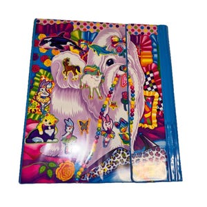 May include: A colorful binder with a whimsical design featuring a white dog, various animal stickers, and a beaded necklace. The binder has a blue spine and a clear pocket. The cover is decorated with vibrant colors and patterns.