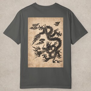 May include: Dark gray t-shirt featuring a detailed black dragon illustration on a tan background. The dragon design includes intricate scales and cloud motifs, creating a vintage aesthetic. The shirt is a comfortable, casual wear item.
