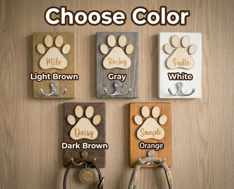 May include: Wooden pet leash holders in light brown, gray, white, dark brown, and orange. Each features a paw print design with a name and a double hook. The text "Choose Color" is at the top.