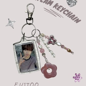 May include: A silver keychain with a photo of a person, pink flower, and beaded charms. The keychain has the text "&TEAM KEYCHAIN" and "EUIJOO". Additional charms include a butterfly and a star.