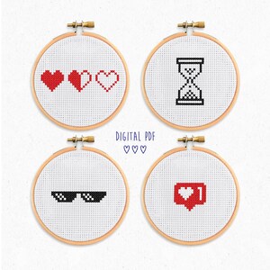 May include: Four cross-stitch embroidery hoops with various designs. The designs include red hearts, an hourglass, pixelated sunglasses, and a red heart with a number one. The text "DIGITAL PDF" and hearts are also included.
