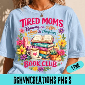 May include: Light blue t-shirt with a colorful graphic. The graphic includes the text "Tired Moms Running on coffee, chaos & chapters" and "Book Club". The design features books, flowers, candles, and a coffee cup with a heart.