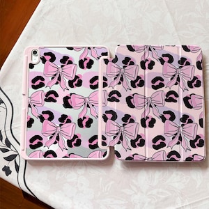 Puede incluir: Funda de tableta rosa con diseño de lazo y estampado de leopardo. La funda presenta un borde rosa claro y un patrón repetido de lazos rosas y manchas de leopardo negras sobre un fondo rosa claro y lavanda.