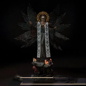 May include: A detailed figurine of a winged figure wearing a long black robe with a white embroidered stole. The figure has a gold halo, a mask, and multiple black wings. It stands on a rocky base decorated with small lit candles and a red creature.