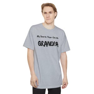 May include: A light gray t-shirt with the text "My favorite Player Calls Me GRANDPA" in black. The shirt is a short-sleeved crew neck style.