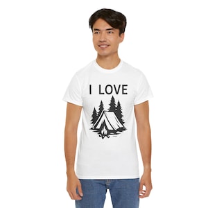 Op de afbeelding: Wit T-shirt met de tekst "I LOVE" boven een zwarte afbeelding van een tent, bomen en een kampvuur. Het shirt is gemaakt van zacht materiaal en is geschikt voor outdoor liefhebbers.