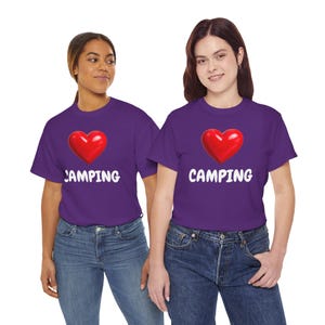 Op de afbeelding: Twee mensen dragen paarse t-shirts met een rode hartafbeelding en het woord "CAMPING" in het wit. De shirts worden gecombineerd met een blauwe jeans. De afbeelding is goed belicht en richt zich op de shirts.