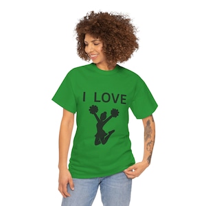 Op de afbeelding: Een groen t-shirt met de tekst "I LOVE" boven een zwart silhouet van een cheerleader die springt en pompons vasthoudt. Het shirt is gemaakt van een zacht materiaal.