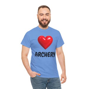 Op de afbeelding: Een lichtblauw t-shirt met een groot rood hart en het woord "ARCHERY" in zwarte letters. Het shirt is gemaakt van een zacht materiaal en is geschikt voor vrijetijdskleding.