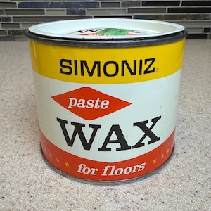 Op de afbeelding: Een cilindervormig metalen blik met Simoniz pastawas voor vloeren. Het etiket heeft een gele bovenband, een wit middengedeelte met een rode ruit met het woord paste, en een rode onderband met de tekst for floors en kleine sterretjes.