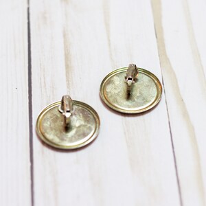 May include: A pair of gold-toned clip-on earrings with round, smooth, metal fronts.
