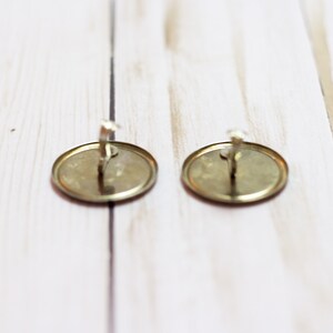 May include: Two gold-colored metal earring backs with a silver-colored hook.