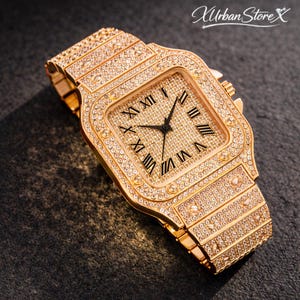 K&ouml;nnte beinhalten: Goldfarbene Armbanduhr mit quadratischem Zifferblatt und Armband, besetzt mit glitzernden Kristallen. Das Zifferblatt hat r&ouml;mische Ziffern und schwarze Zeiger. Ein luxuri&ouml;ses Accessoire.