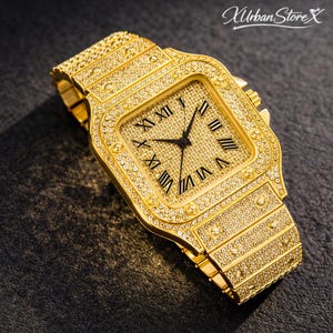 K&ouml;nnte beinhalten: Eine goldfarbene Armbanduhr mit quadratischem Zifferblatt und passendem Armband. Die Uhr ist mit kleinen, funkelnden Steinen besetzt. Das Zifferblatt hat schwarze r&ouml;mische Ziffern und Zeiger. Der Markenname "Urban Store X" befindet sich oben rechts.