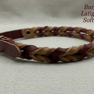 May include: A braided leather collar featuring alternating burgundy and soft sand colored strands. The collar includes a silver-toned metal buckle and a leather strap end. Text on the image reads: Burgundy Latigo with Soft Sand.