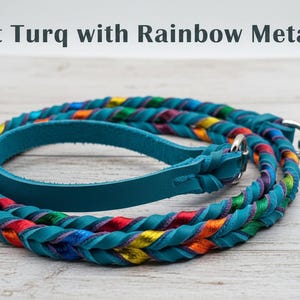 May include: A braided dog leash featuring soft turquoise leather strands intertwined with rainbow metallic accents. The leash includes a solid turquoise leather handle loop and a silver-toned metal swivel snap hook. Text reads: Soft Turq with Rainbow Metallic.