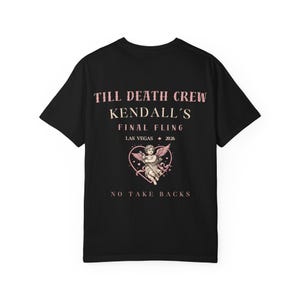 May include: Black t-shirt featuring pink text and a heart-shaped graphic. The text reads "TILL DEATH CREW KENDALL'S FINAL FLING LAS VEGAS 2026" above an angel graphic. The text "NO TAKE BACKS" is below the graphic.