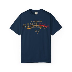May include: Navy blue t-shirt featuring a graphic of a VU meter with the text "L-LEVEL dB" and "VU". The meter's scale ranges from 20 to +3, with a needle indicating a level. The design is in yellow, orange, and red.