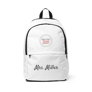 Peut inclure: Sac à dos blanc avec bordure noire et poignée noire. L'avant présente un motif circulaire avec le texte "WORLD'S BEST TEACHER!" et un crayon rouge. En dessous, le nom "Mrs. Miller" en cursive.