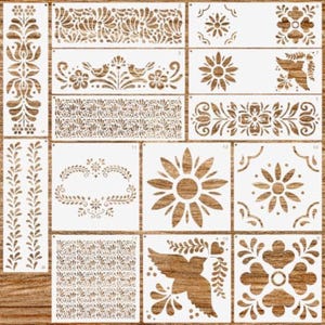 May include: A collection of white plastic stencils featuring various patterns including floral motifs, birds, geometric shapes, and repeating leaf borders. Each stencil is numbered and displays intricate cutouts for decorative painting projects.