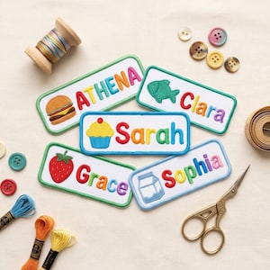 Pode incluir: Cinco emblemas retangulares bordados com nomes e ícones coloridos: um hambúrguer com o nome Athena, um peixe com Clara, um cupcake com Sarah, um morango com Grace e uma caixa de leite com o nome Sophia.