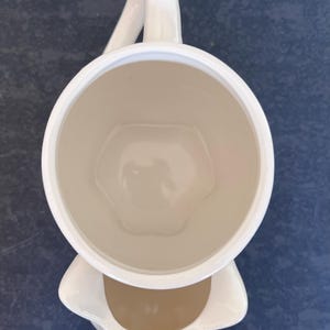 Może przedstawiać: Zestaw trzech ceramicznych kubk&oacute;w z nakrapianym, matowym wykończeniem. Kubki są w odcieniach kremu, jasnoszarym i ciemnoszarym. Każdy kubek ma prosty, minimalistyczny design i zaokrąglony uchwyt.