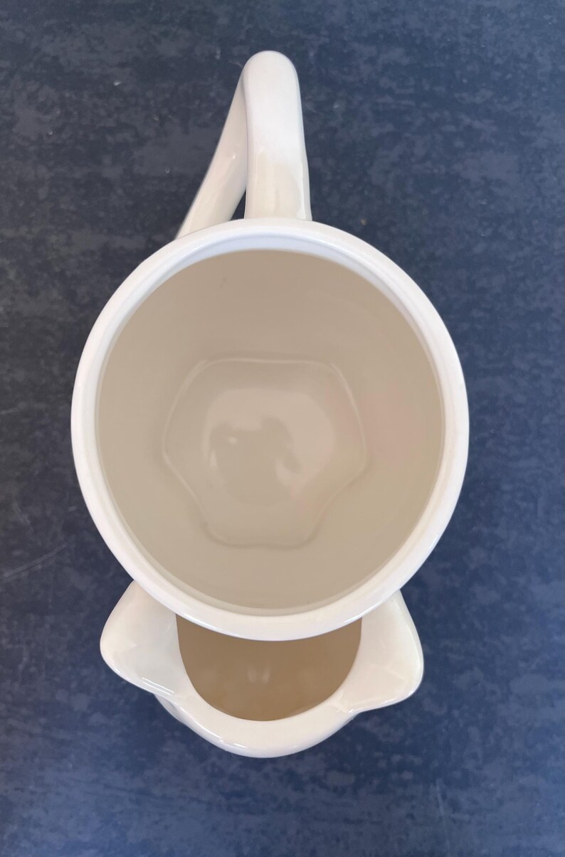Może przedstawiać: Zestaw trzech ceramicznych kubk&oacute;w z nakrapianym, matowym wykończeniem. Kubki są w odcieniach kremu, jasnoszarym i ciemnoszarym. Każdy kubek ma prosty, minimalistyczny design i zaokrąglony uchwyt.