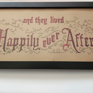 May include: A framed cross-stitch with the text "and they lived Happily ever After" in a red and brown font with green vines surrounding the text.