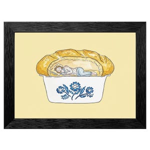 May include: A framed art print depicts a person sleeping inside a baked bread loaf, resting in a white casserole dish with blue floral designs. The background is a soft yellow, and the frame is black.