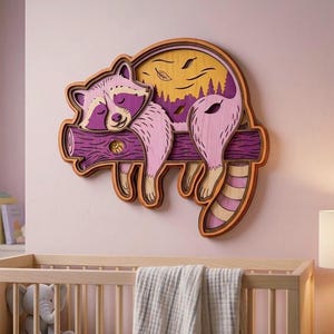 May include: A multi-layered wooden wall art piece featuring a sleeping raccoon resting on a purple branch. The design incorporates shades of pink, purple, and yellow, with a circular background depicting a forest silhouette and falling leaves.